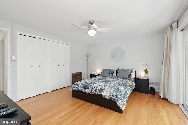 bedroom with a ceiling fan, two closets, and light wood-style flooring