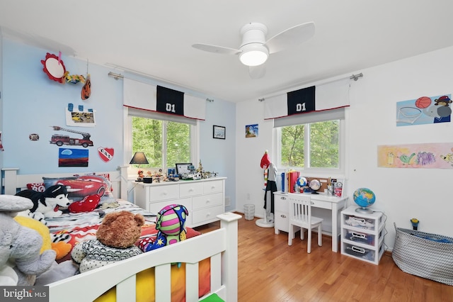 bedroom with a ceiling fan, light wood finished floors, and multiple windows