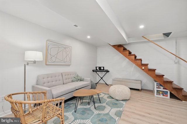 living area with recessed lighting, baseboards, wood finished floors, and stairway