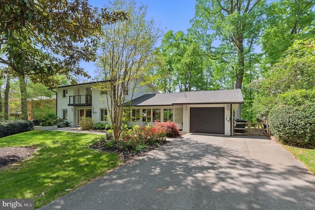 view of front facade featuring driveway, a gate, a balcony, a front lawn, and an attached garage