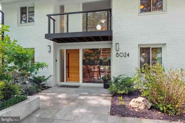 doorway to property featuring a balcony and brick siding