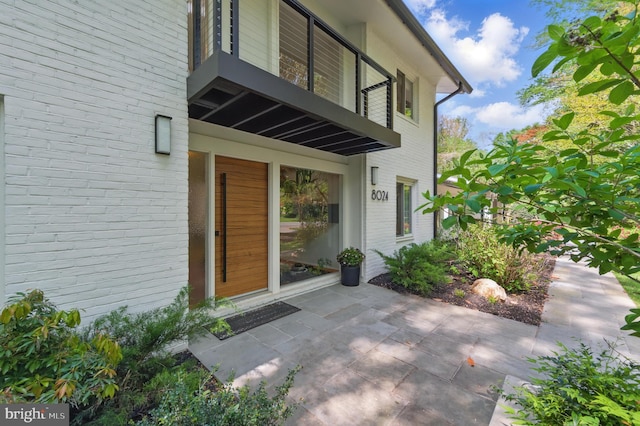 doorway to property with a patio and brick siding