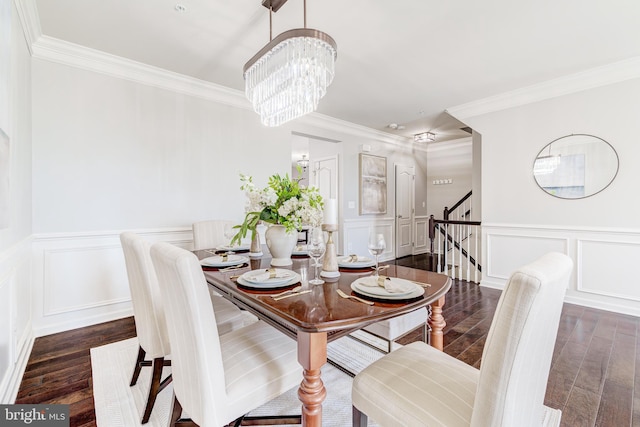 dining area featuring stairway, ornamental molding, a decorative wall, and dark wood-style flooring