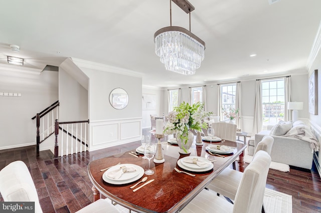 dining area featuring crown molding, wainscoting, wood finished floors, a decorative wall, and stairs