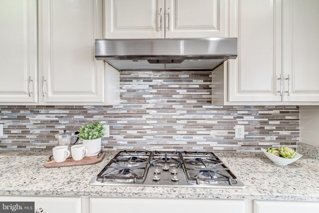 kitchen featuring stainless steel gas stovetop, decorative backsplash, white cabinets, and under cabinet range hood