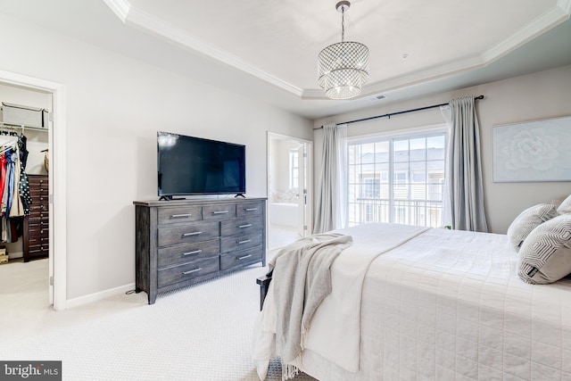 bedroom featuring crown molding, a tray ceiling, light carpet, and a walk in closet