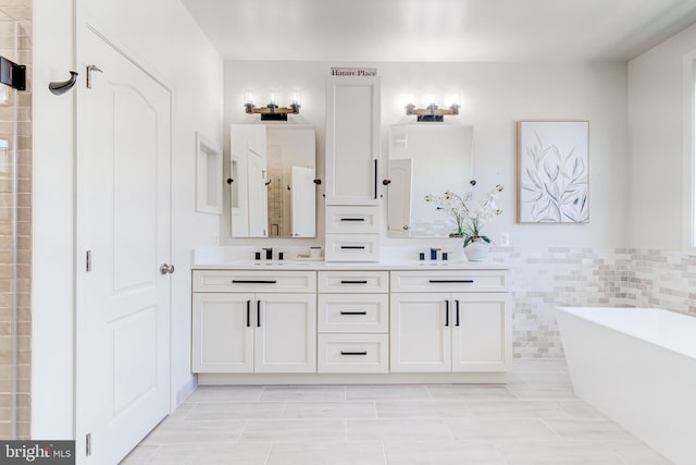 bathroom with double vanity, a sink, a freestanding bath, and a stall shower