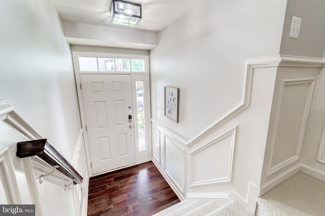 entryway with dark wood-style flooring, a decorative wall, and wainscoting