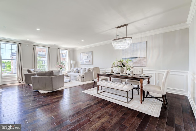 dining room featuring crown molding, dark wood finished floors, a decorative wall, and a notable chandelier