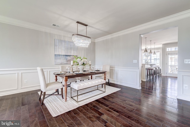 dining space featuring visible vents, dark wood-style floors, a notable chandelier, ornamental molding, and a decorative wall