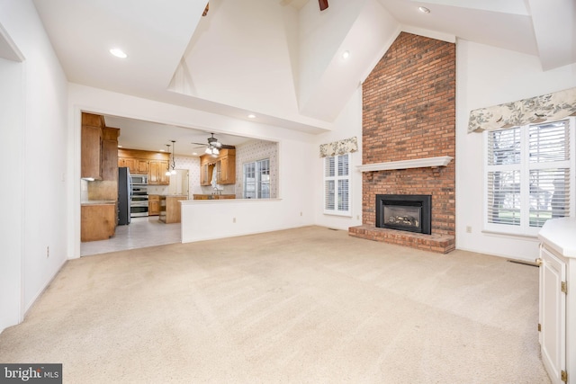 unfurnished living room with high vaulted ceiling, ceiling fan, light carpet, a brick fireplace, and recessed lighting