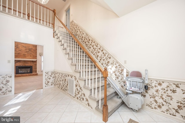 staircase featuring wainscoting, visible vents, tile patterned flooring, and wallpapered walls