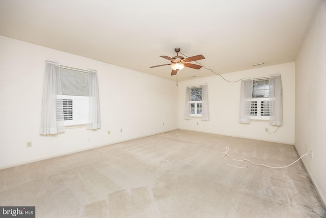 carpeted spare room featuring visible vents and a ceiling fan