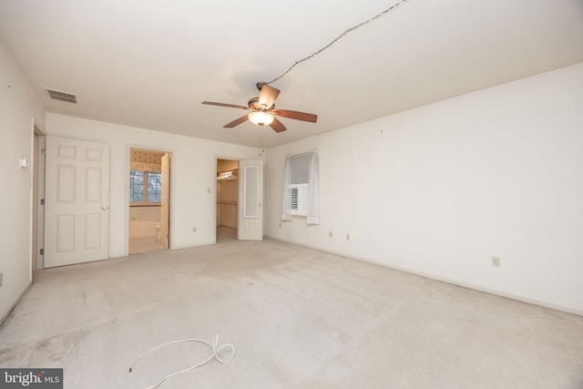 unfurnished bedroom featuring ensuite bathroom, a walk in closet, baseboards, carpet flooring, and visible vents