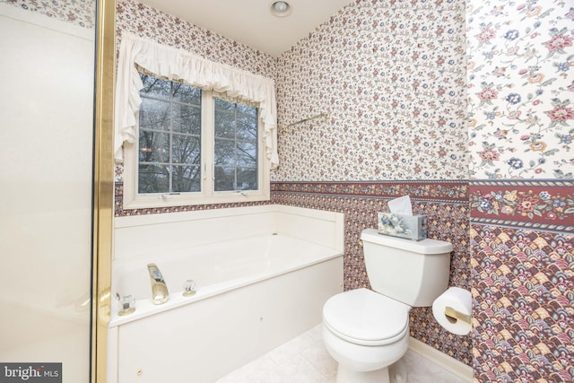 full bath featuring tile patterned floors, a wainscoted wall, toilet, wallpapered walls, and a garden tub