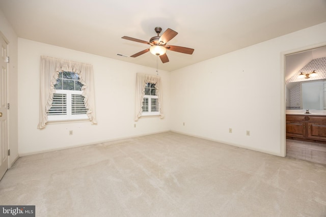 unfurnished bedroom with a sink, connected bathroom, light carpet, baseboards, and visible vents