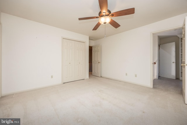 unfurnished bedroom featuring baseboards, a closet, a ceiling fan, and light colored carpet