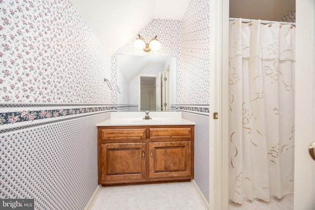 full bath with wallpapered walls, lofted ceiling, tile patterned floors, and vanity