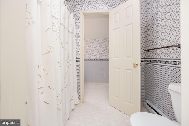 full bath featuring a baseboard heating unit, toilet, tile patterned floors, and curtained shower