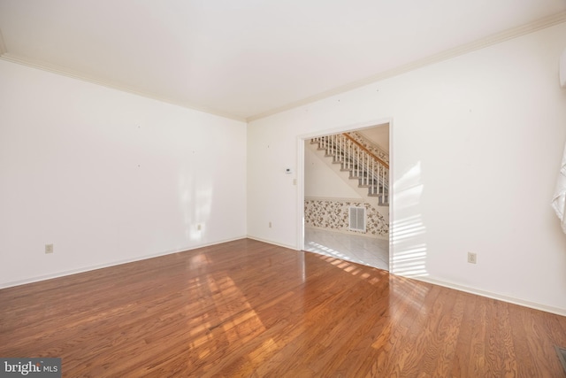 unfurnished room with stairway, ornamental molding, baseboards, and wood finished floors