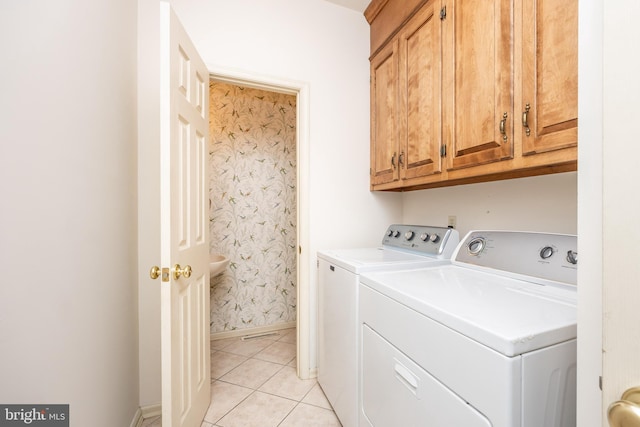 laundry area featuring washing machine and dryer, baseboards, cabinet space, and light tile patterned flooring
