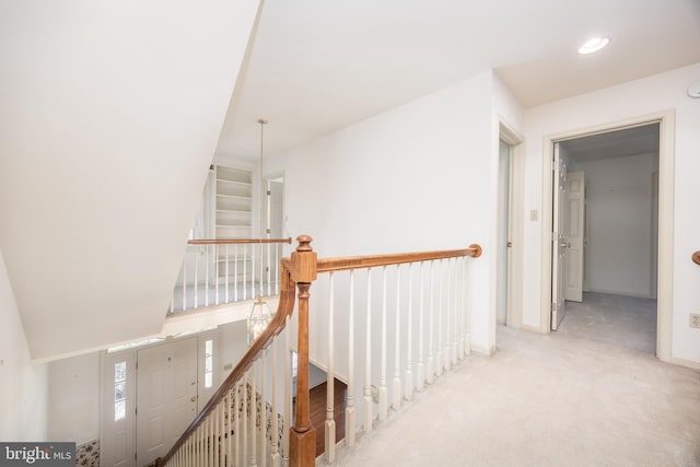 hallway with carpet flooring and an upstairs landing