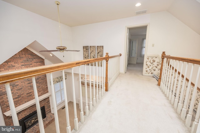 hallway with lofted ceiling, an upstairs landing, and visible vents