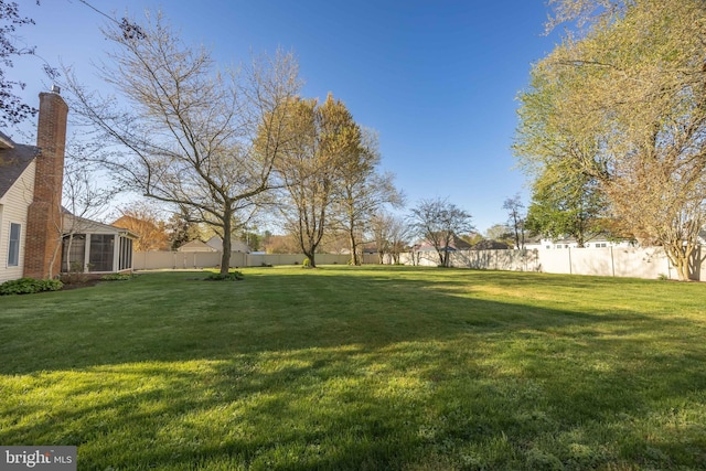view of yard with a fenced backyard and a sunroom