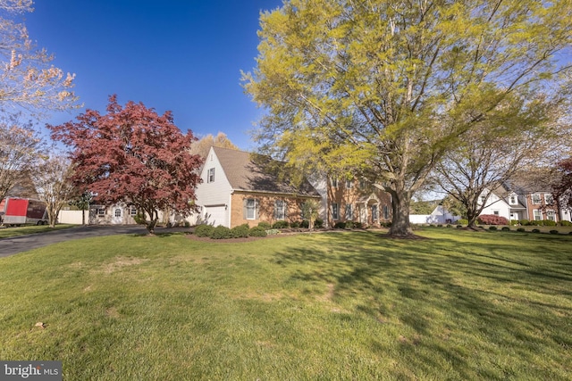 view of yard featuring an attached garage and aphalt driveway