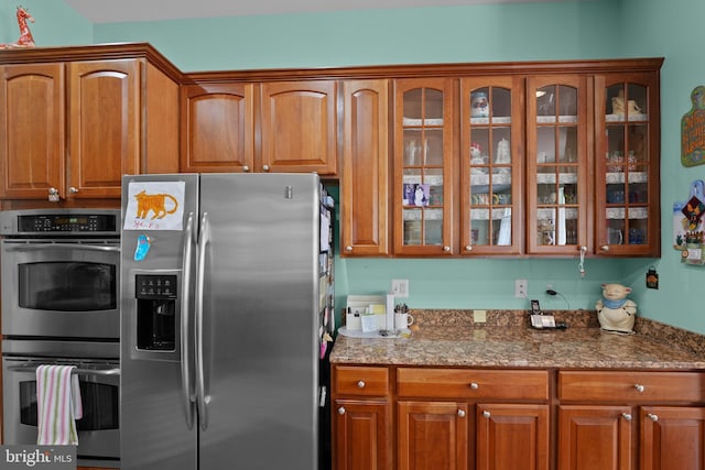 6609 Cheney Way, Gainesville, VA 20155 - kitchen with stainless steel appliances, brown cabinets, stone counters, and glass insert cabinets