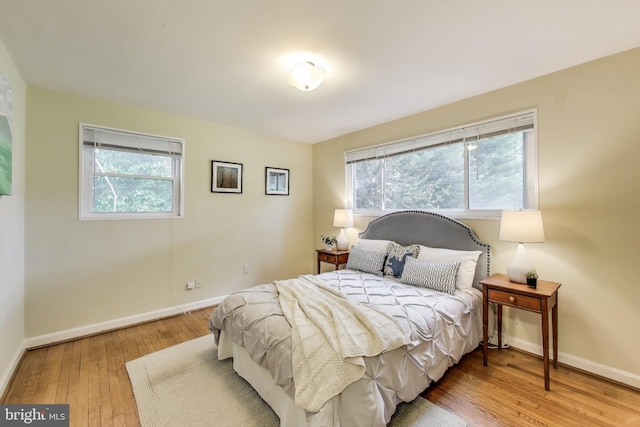 bedroom with baseboards, multiple windows, and hardwood / wood-style floors