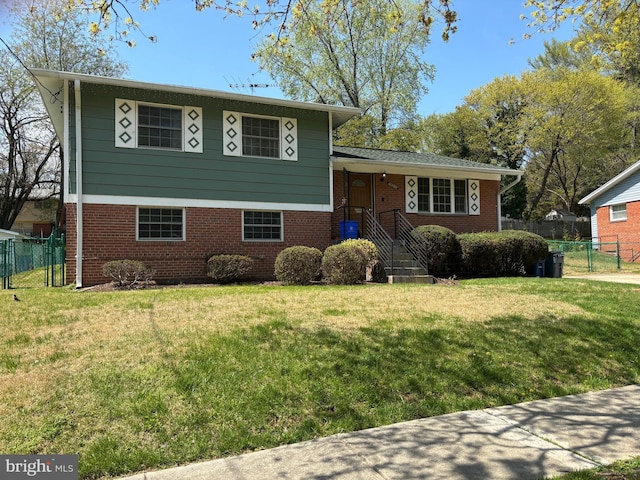 split level home with fence, a front yard, and brick siding
