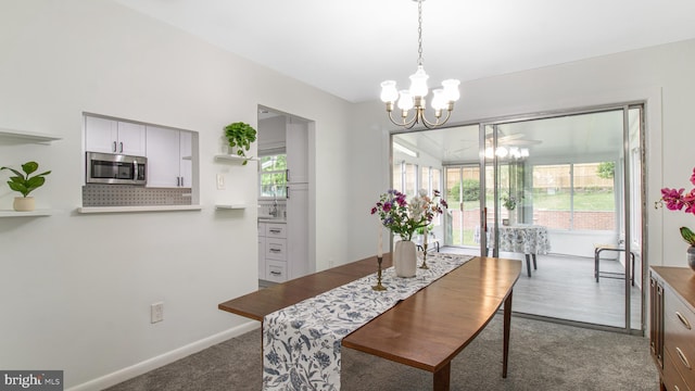 carpeted dining area featuring baseboards and a notable chandelier