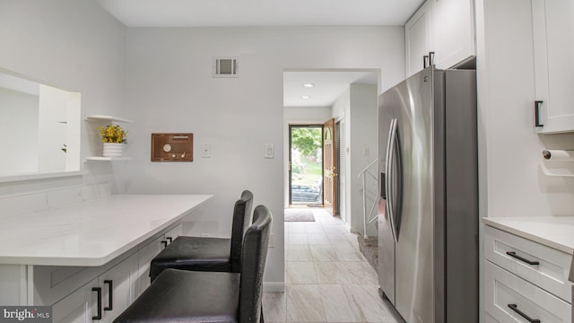 kitchen featuring visible vents, open shelves, a breakfast bar, white cabinets, and stainless steel fridge with ice dispenser