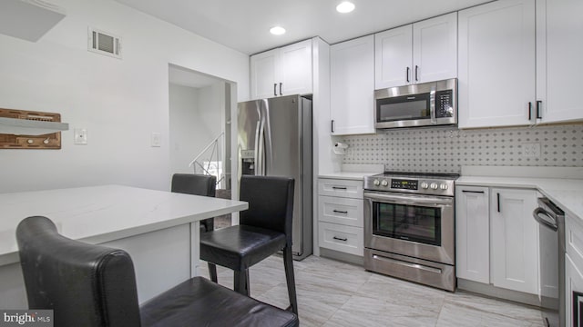 kitchen featuring stainless steel appliances, visible vents, white cabinetry, and tasteful backsplash