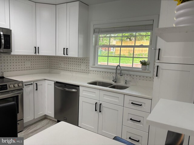 kitchen featuring a sink, white cabinetry, appliances with stainless steel finishes, and tasteful backsplash