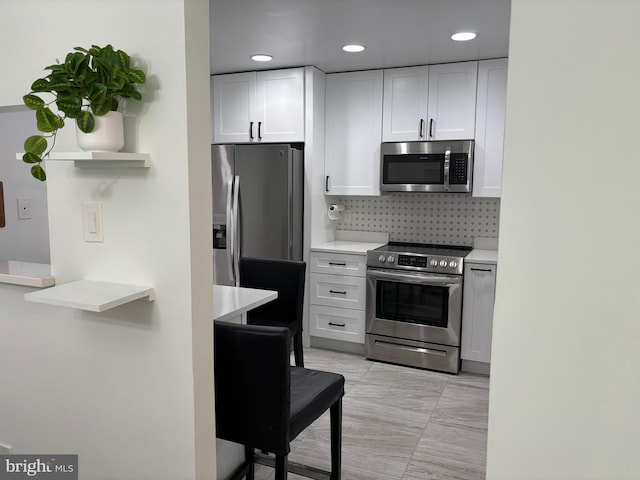 kitchen with white cabinets, open shelves, appliances with stainless steel finishes, light countertops, and backsplash
