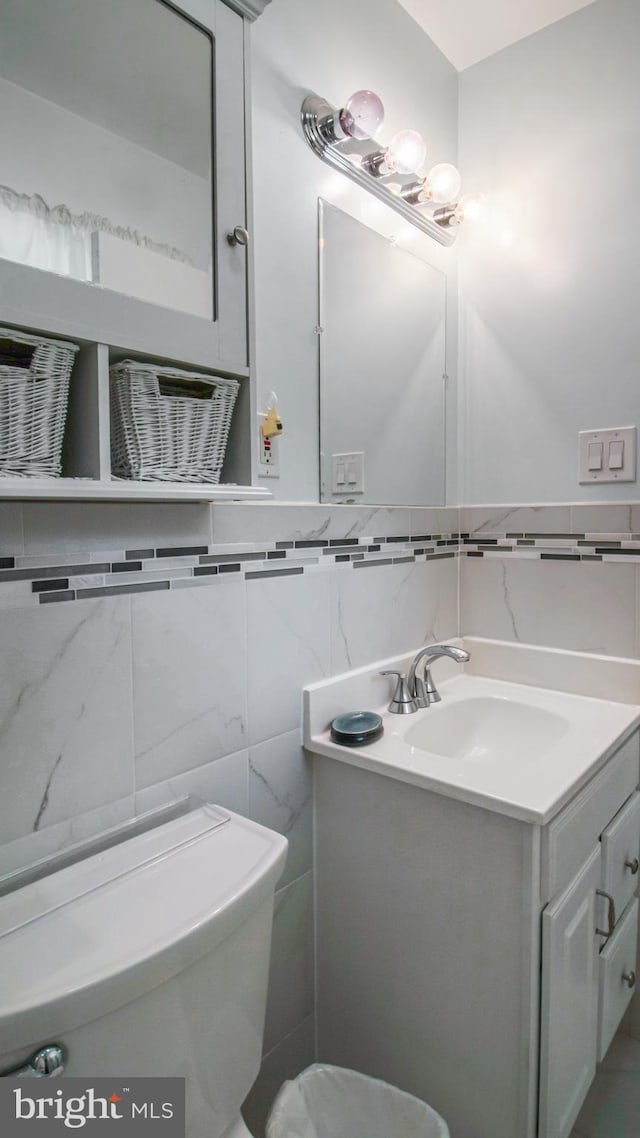 bathroom with vanity, toilet, and tile walls