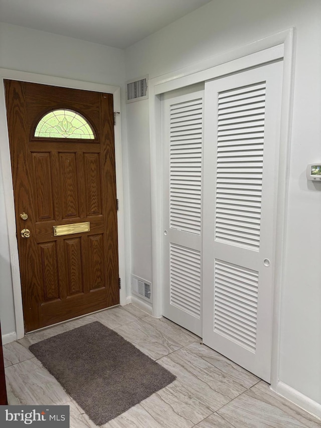 foyer entrance featuring visible vents and baseboards
