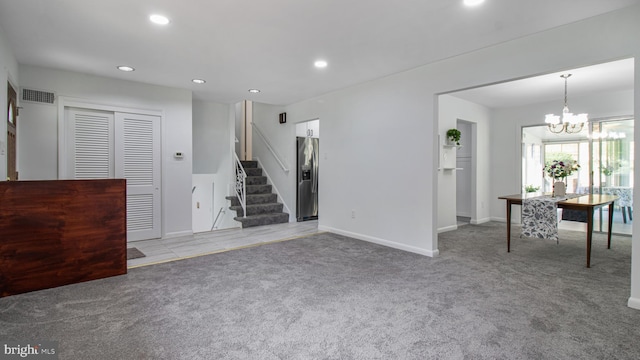unfurnished living room with stairway, baseboards, an inviting chandelier, light carpet, and recessed lighting