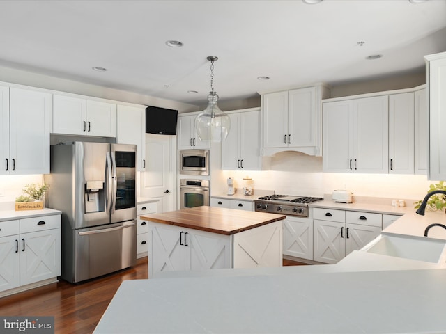 kitchen with butcher block countertops, dark wood-style floors, white cabinets, a sink, and appliances with stainless steel finishes