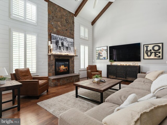 living room with beamed ceiling, high vaulted ceiling, a stone fireplace, and wood finished floors