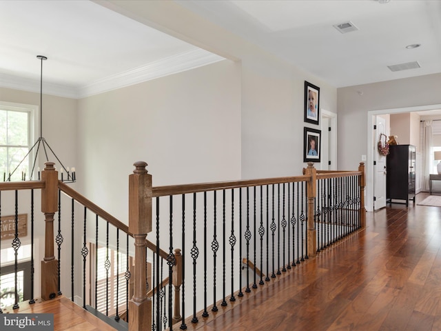 hallway with visible vents, wood finished floors, and an upstairs landing