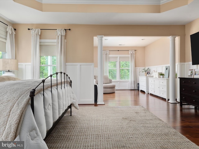 bedroom with a decorative wall, a wainscoted wall, and dark wood-style floors