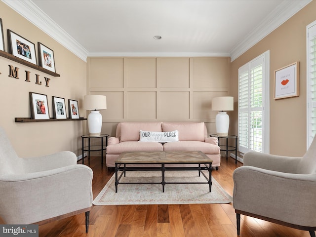 living area with crown molding, a decorative wall, and wood finished floors