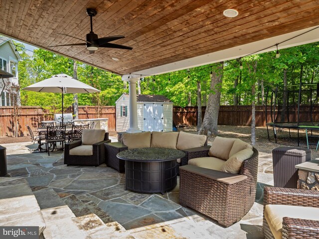 view of patio with outdoor dining area, a trampoline, an outdoor structure, a fenced backyard, and a shed