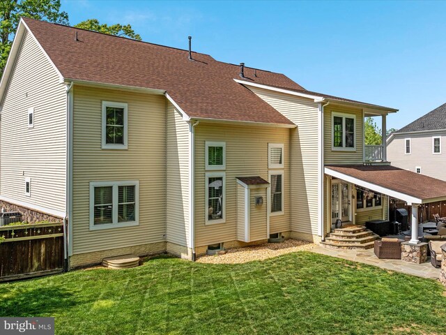 rear view of property with fence, roof with shingles, a jacuzzi, a patio area, and a yard