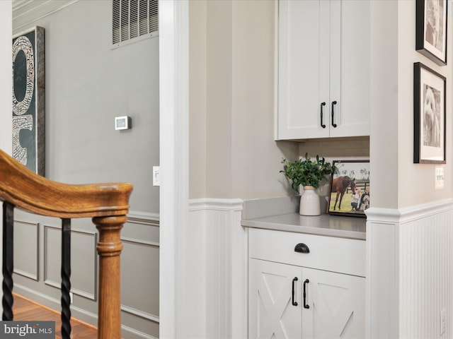 bar featuring wood finished floors, a decorative wall, and a wainscoted wall