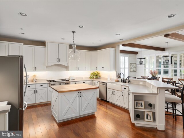 kitchen with a peninsula, wooden counters, a breakfast bar area, a sink, and stainless steel appliances