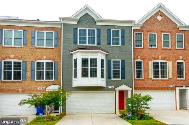 townhome / multi-family property with concrete driveway, brick siding, and a garage